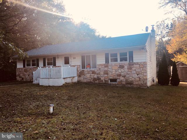 back of house with crawl space, a chimney, and stone siding