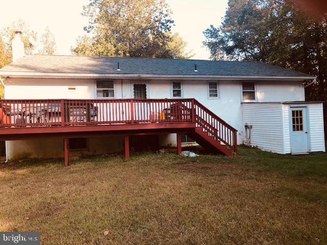 back of property with a lawn, a wooden deck, stairs, and a chimney