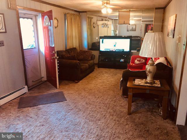 living area featuring carpet floors, a ceiling fan, a baseboard heating unit, and ornamental molding