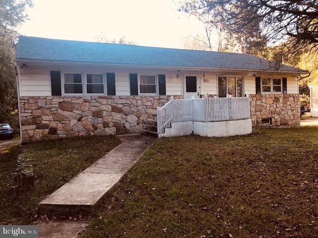 ranch-style house featuring a porch and stone siding
