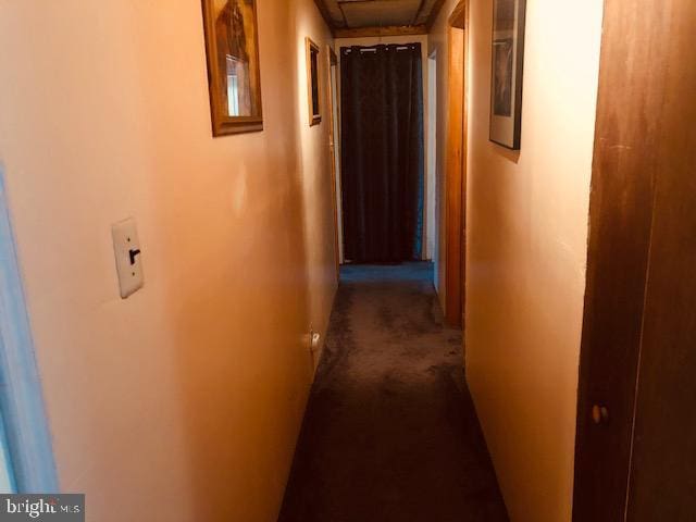 corridor featuring attic access and dark carpet