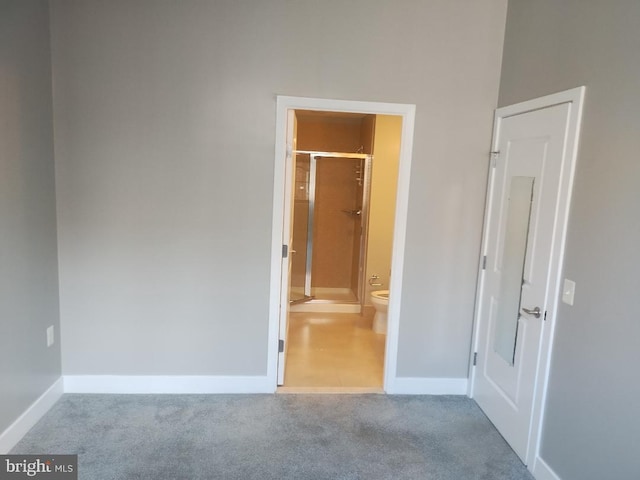 unfurnished bedroom featuring baseboards, ensuite bath, and carpet floors