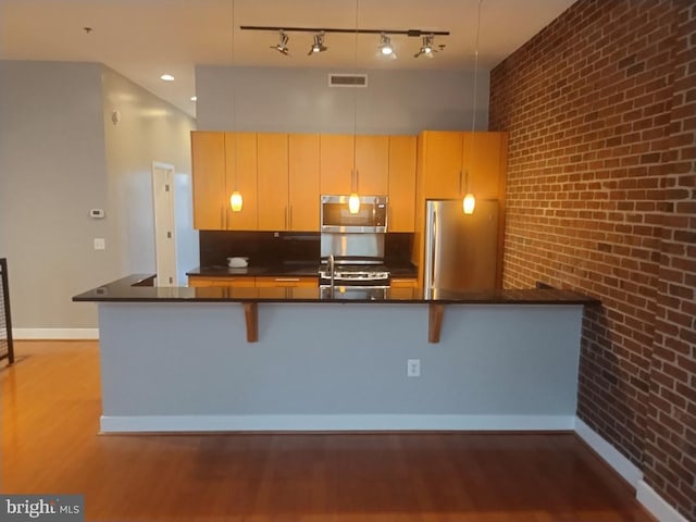 kitchen with appliances with stainless steel finishes, wood finished floors, dark countertops, and baseboards