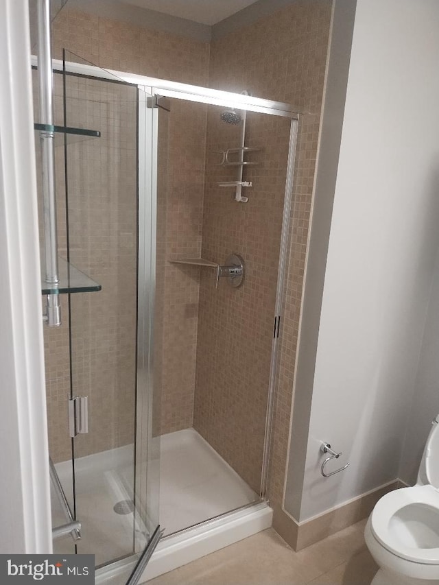 bathroom featuring toilet, a stall shower, and tile patterned floors