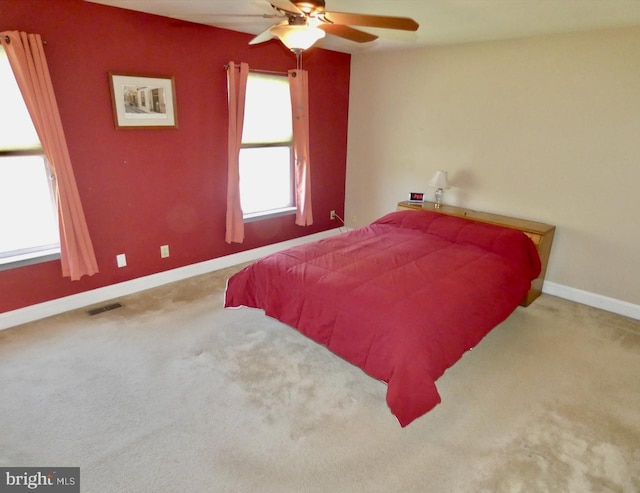 carpeted bedroom with baseboards, a ceiling fan, and visible vents