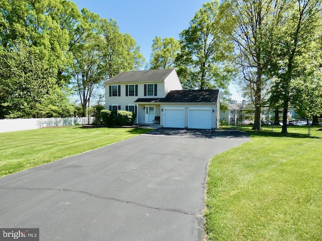 view of front of home featuring an attached garage, fence, a front yard, and aphalt driveway