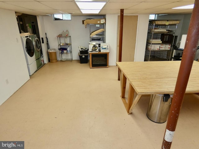 below grade area with a drop ceiling and washing machine and clothes dryer