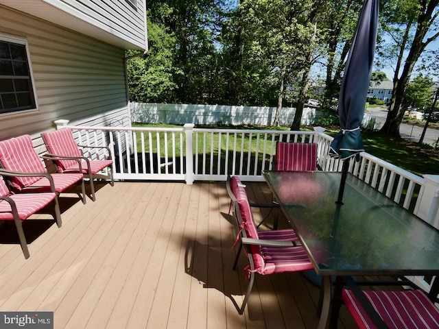 wooden deck with a fenced backyard, outdoor dining space, and a yard