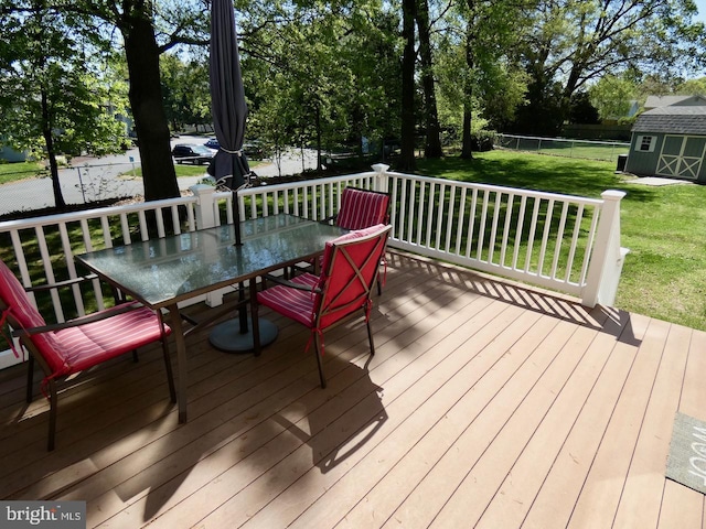 wooden deck with a fenced backyard, a storage unit, a lawn, an outbuilding, and outdoor dining space