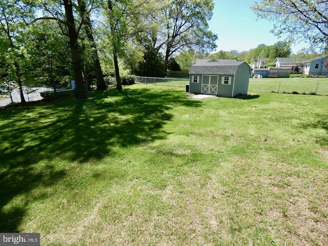 view of yard with a fenced backyard, a storage unit, and an outbuilding