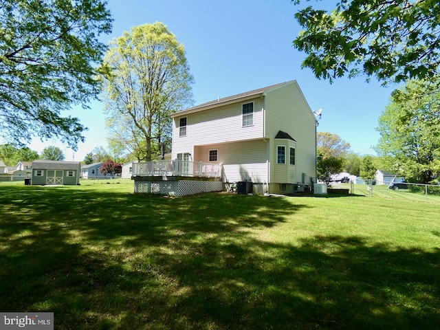 back of house with a lawn, a deck, central AC, an outdoor structure, and a storage unit