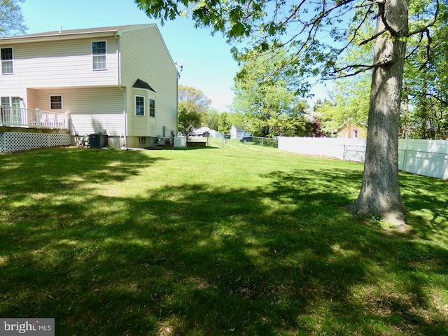 view of yard with fence, a wooden deck, and cooling unit