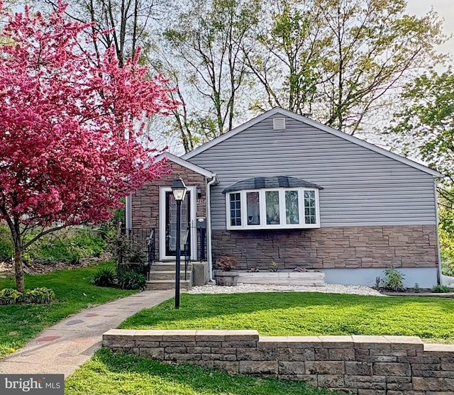 view of front of property with a front lawn and stone siding