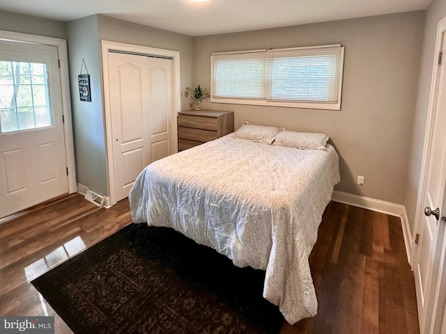 bedroom with dark wood-style flooring, baseboards, and a closet