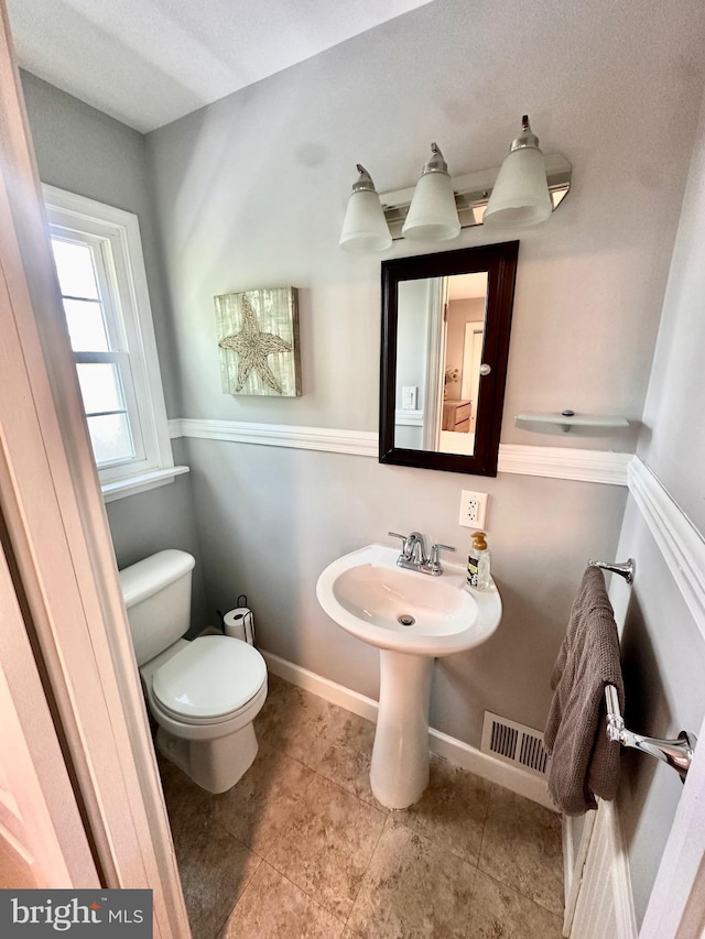 bathroom featuring toilet, tile patterned floors, visible vents, and baseboards
