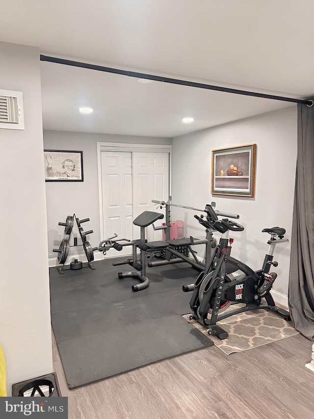 workout room featuring baseboards, recessed lighting, and wood finished floors
