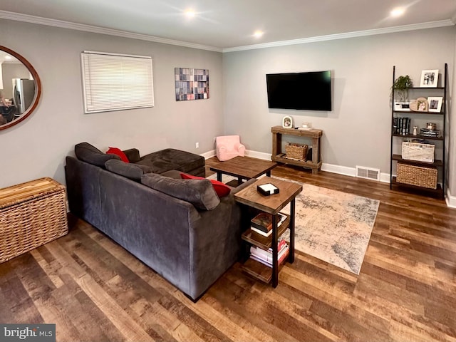 living area with visible vents, baseboards, crown molding, and wood finished floors