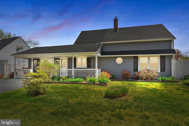 single story home with a porch, a chimney, roof with shingles, a lawn, and fence