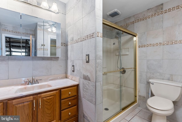 full bath with vanity, toilet, tile patterned floors, tile walls, and a shower stall