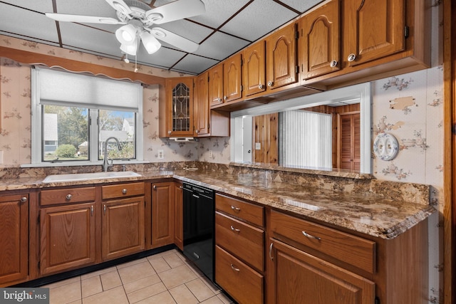 kitchen with brown cabinetry, ceiling fan, wallpapered walls, a sink, and dishwasher