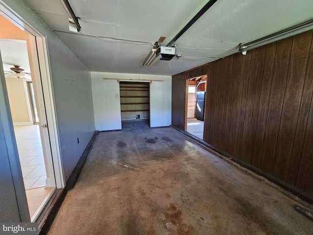 garage with baseboards, ceiling fan, a garage door opener, and wood walls