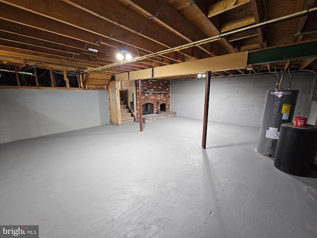 unfinished below grade area featuring stairs, concrete block wall, and electric water heater