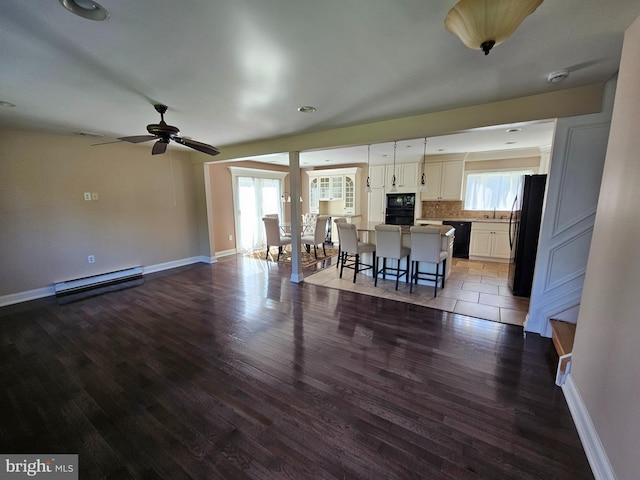 living room featuring baseboards, ceiling fan, wood finished floors, and baseboard heating