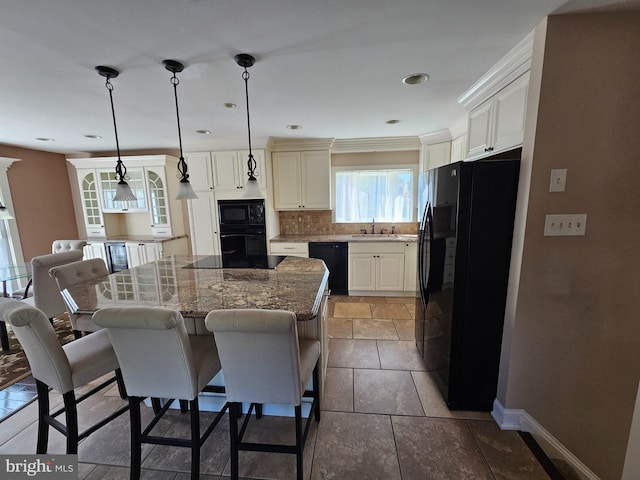 kitchen with baseboards, a kitchen breakfast bar, a center island, dark stone countertops, and black appliances