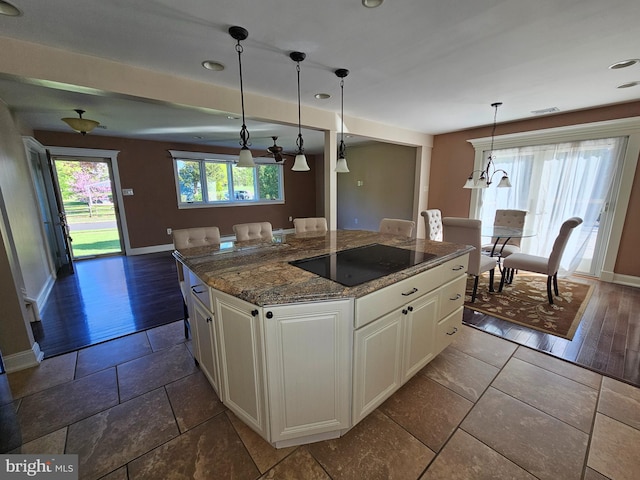 kitchen featuring baseboards, dark stone counters, white cabinetry, and black electric stovetop
