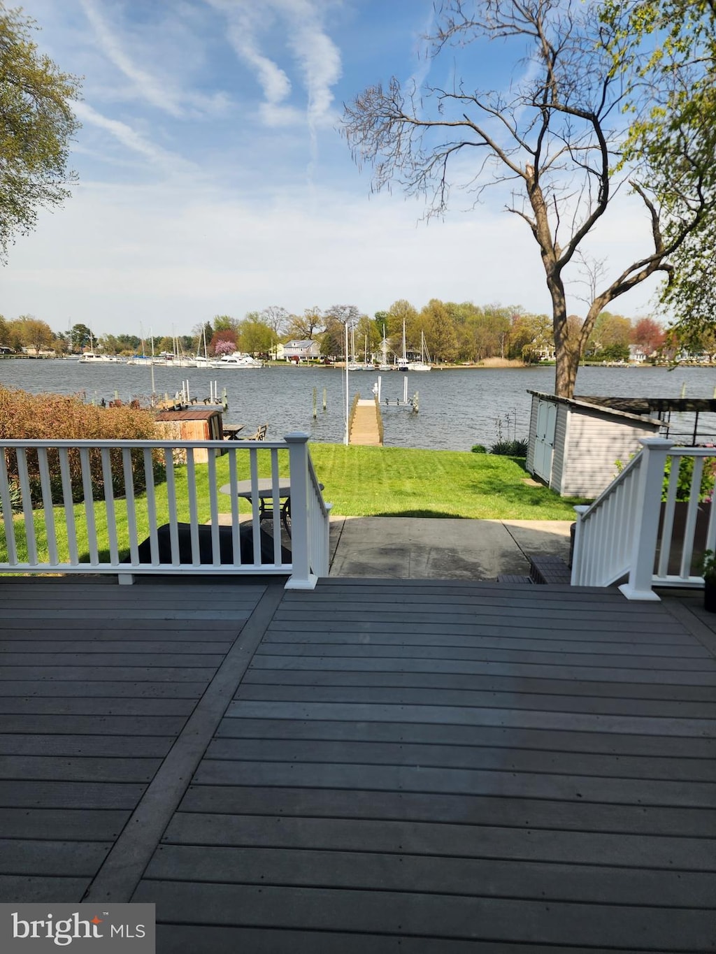 wooden terrace with a yard, a boat dock, and a water view