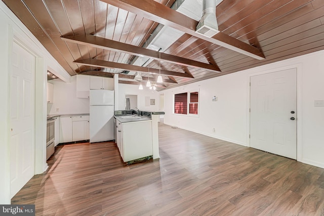 kitchen featuring freestanding refrigerator, open floor plan, vaulted ceiling with beams, white cabinetry, and a sink