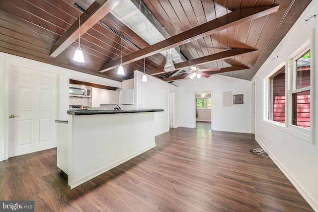 kitchen with dark countertops, open floor plan, vaulted ceiling with beams, stainless steel microwave, and dark wood finished floors