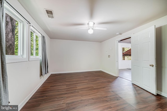 spare room with a healthy amount of sunlight, ceiling fan, dark wood-type flooring, and visible vents