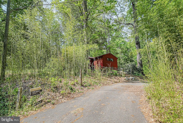 view of road featuring a wooded view and aphalt driveway