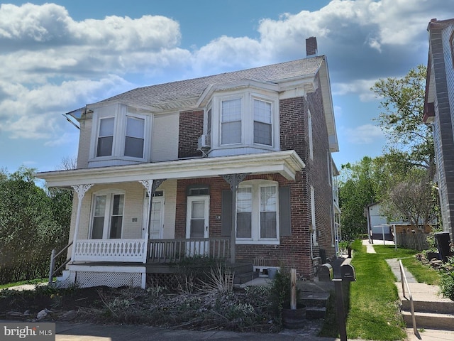view of front of property featuring a chimney, brick siding, and a porch