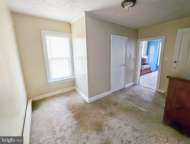 unfurnished dining area with baseboards, crown molding, and carpet