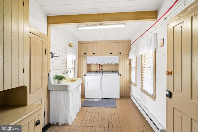 306 Bohemia Ave, Chesapeake City, MD 21915 - clothes washing area with washer and dryer, cabinet space, baseboard heating, wood walls, and light wood-type flooring