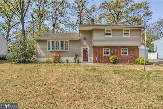 tri-level home with fence, a front yard, a chimney, brick siding, and entry steps