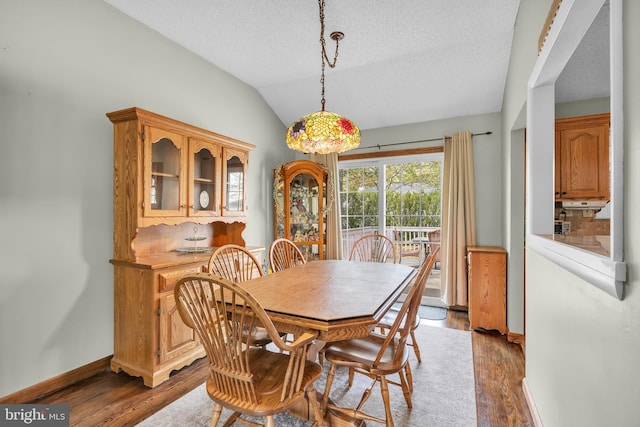 dining space with baseboards, a textured ceiling, wood finished floors, and vaulted ceiling