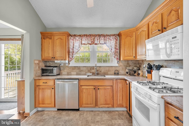kitchen featuring a sink, lofted ceiling, white appliances, and tasteful backsplash