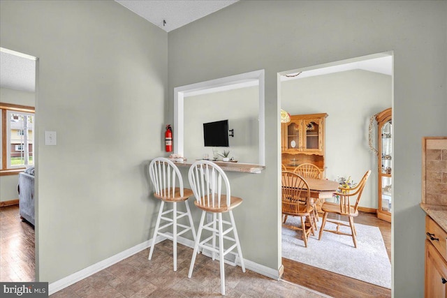 kitchen with baseboards, a breakfast bar area, and wood finished floors