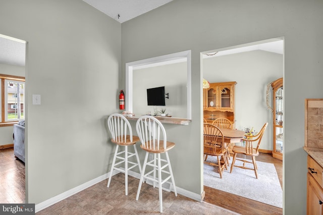kitchen with baseboards, light wood-style flooring, and a breakfast bar area
