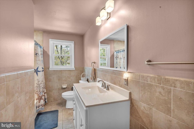 full bathroom featuring vanity, wainscoting, toilet, tile walls, and tile patterned floors