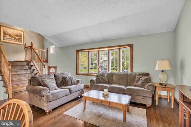 living area with stairway, a textured ceiling, vaulted ceiling, and wood finished floors