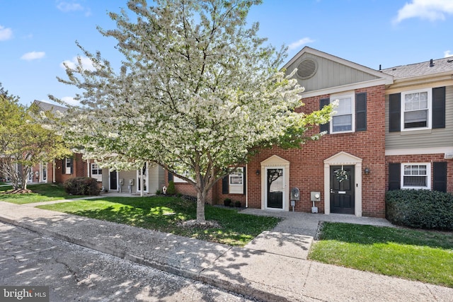 townhome / multi-family property with a front yard and brick siding