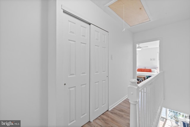 hall with baseboards, attic access, wood finished floors, and an upstairs landing