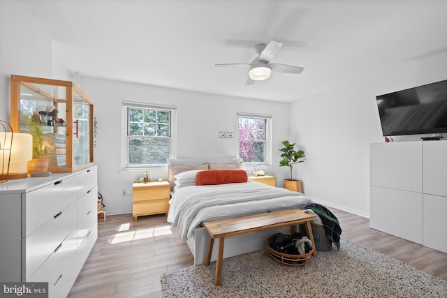 bedroom with baseboards, ceiling fan, and light wood-style flooring