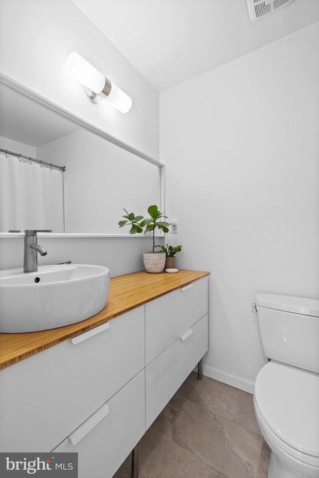 bathroom with vanity, baseboards, toilet, and visible vents