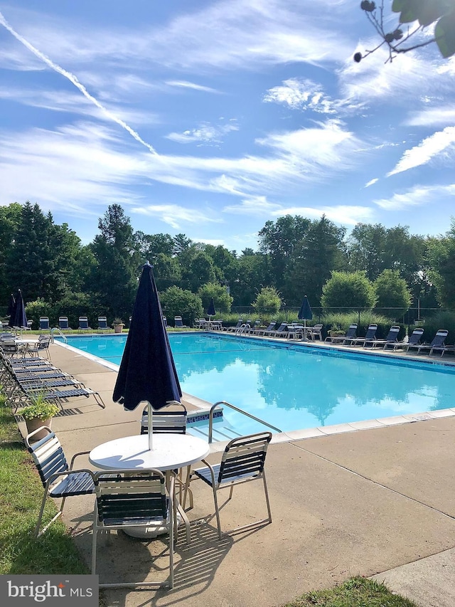 pool with a patio area and fence
