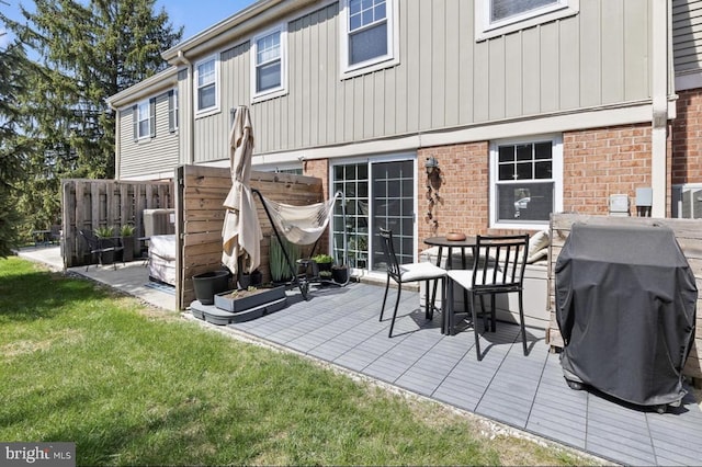 back of house with a yard, brick siding, board and batten siding, and fence